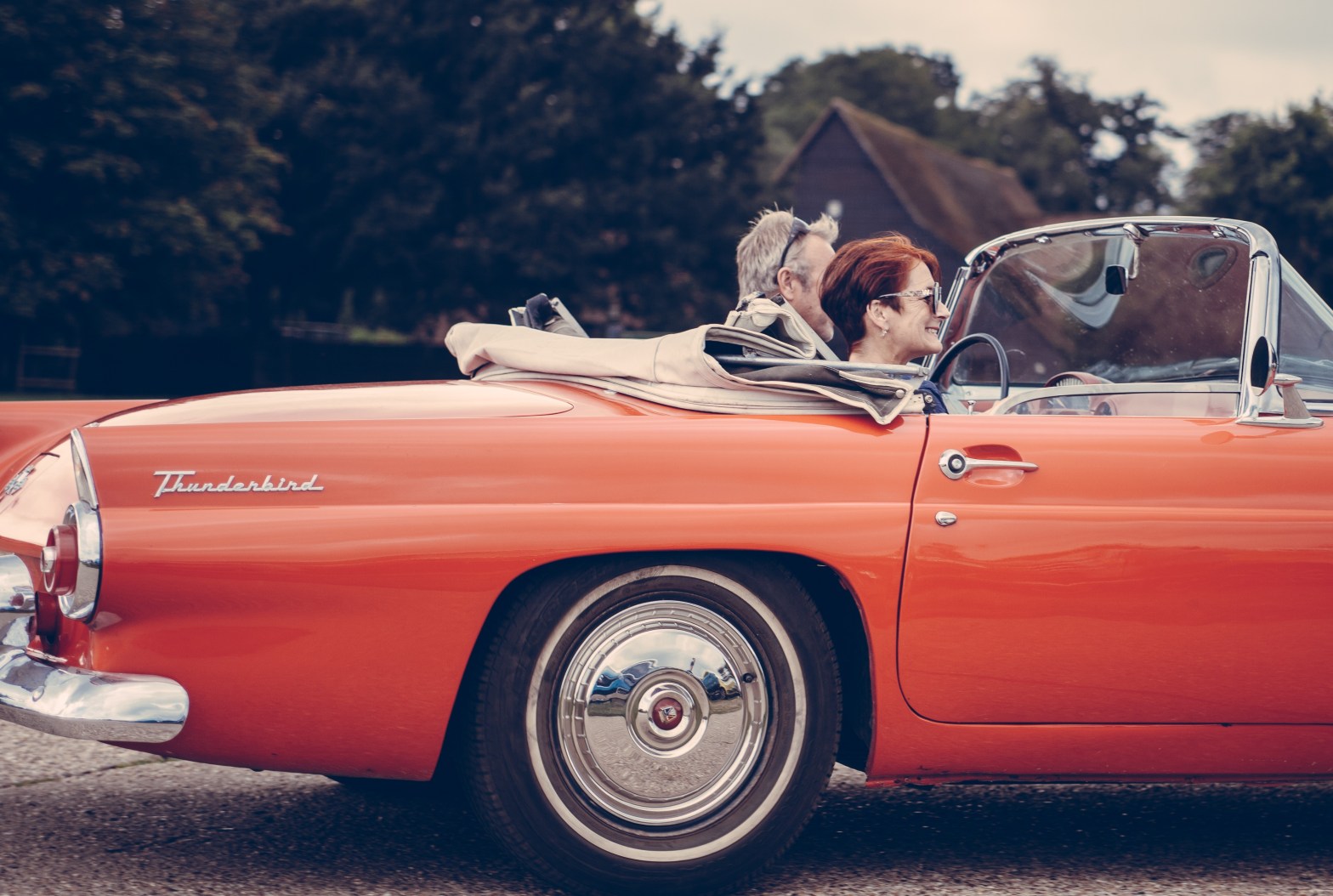 Couple riding in a red Thunderbird with the top down. Photo by Clem Onojeghuo on Unsplash